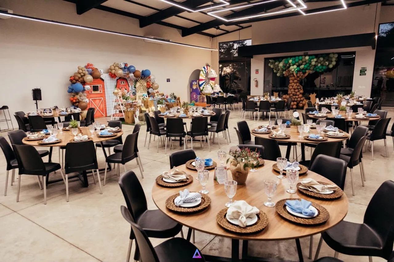 Salão principal do 3:16, com mesas redondas de madeira, cadeiras pretas e decoração em tons terrosos e azuis
