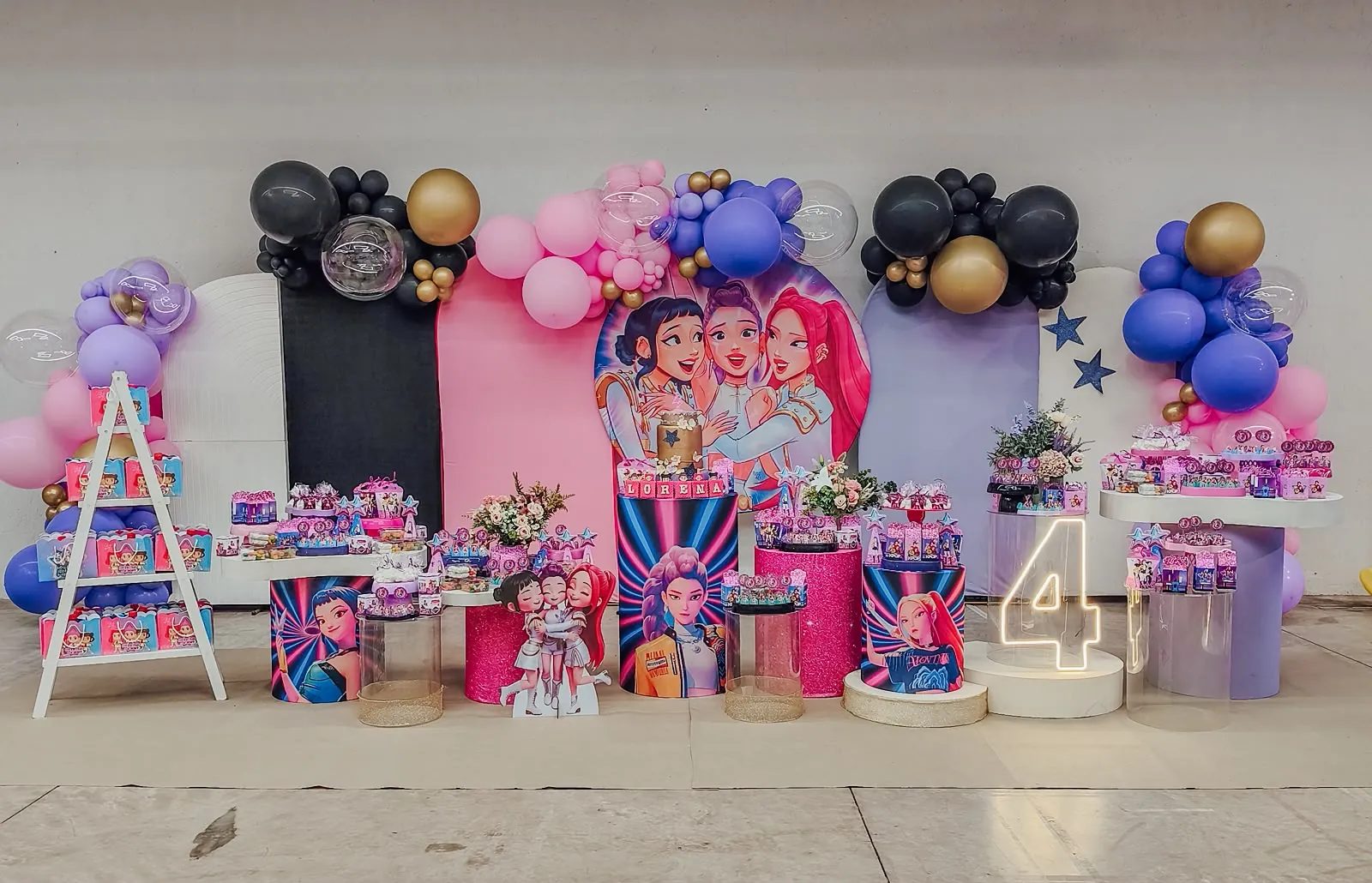 Decoração com tema pop, com painel de personagens e balões em rosa, roxo e preto