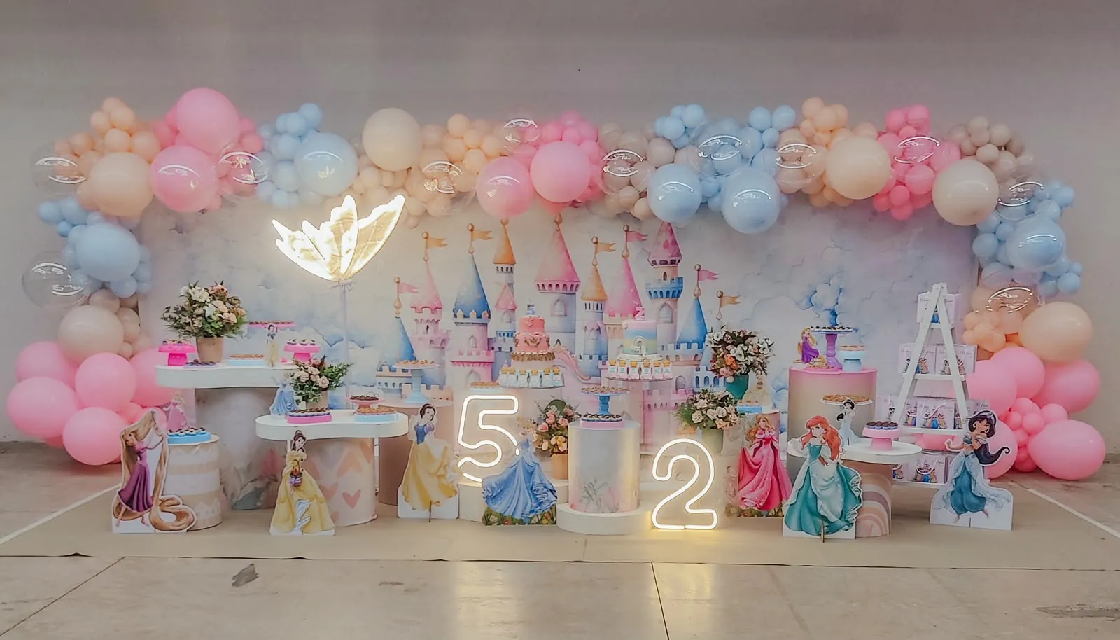 Decoração com tema princesas Disney, com castelo em aquarela ao fundo e balões em rosa e azul